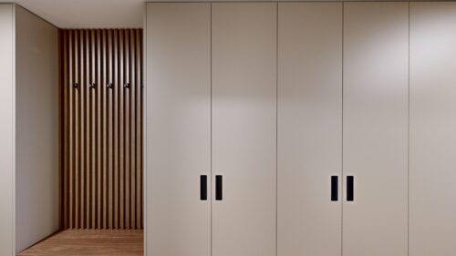 Beige built-in cabinets with black handles along a wall; wooden slat panel on the left.