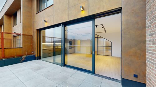 Modern building facade with large glass doors and interior staircase visible through the glass doors outside the entrance to a contemporary space.