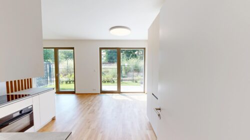 Bright modern kitchen with white cabinetry and large glass doors opening to a green garden behind.