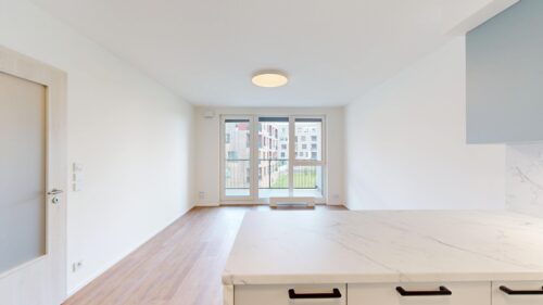 Bright open-plan kitchen with marble island, white cabinetry, and a large window door to a balcony in daylight.