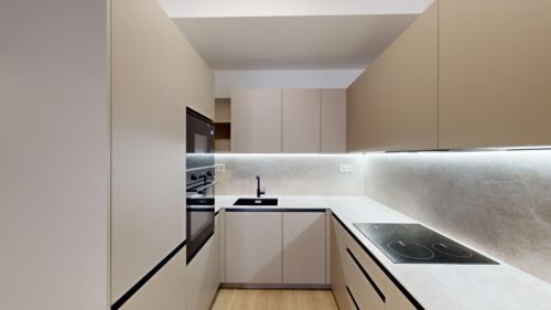 Modern beige kitchen with built-in oven, induction cooktop, and minimalist flat-panel cabinets.